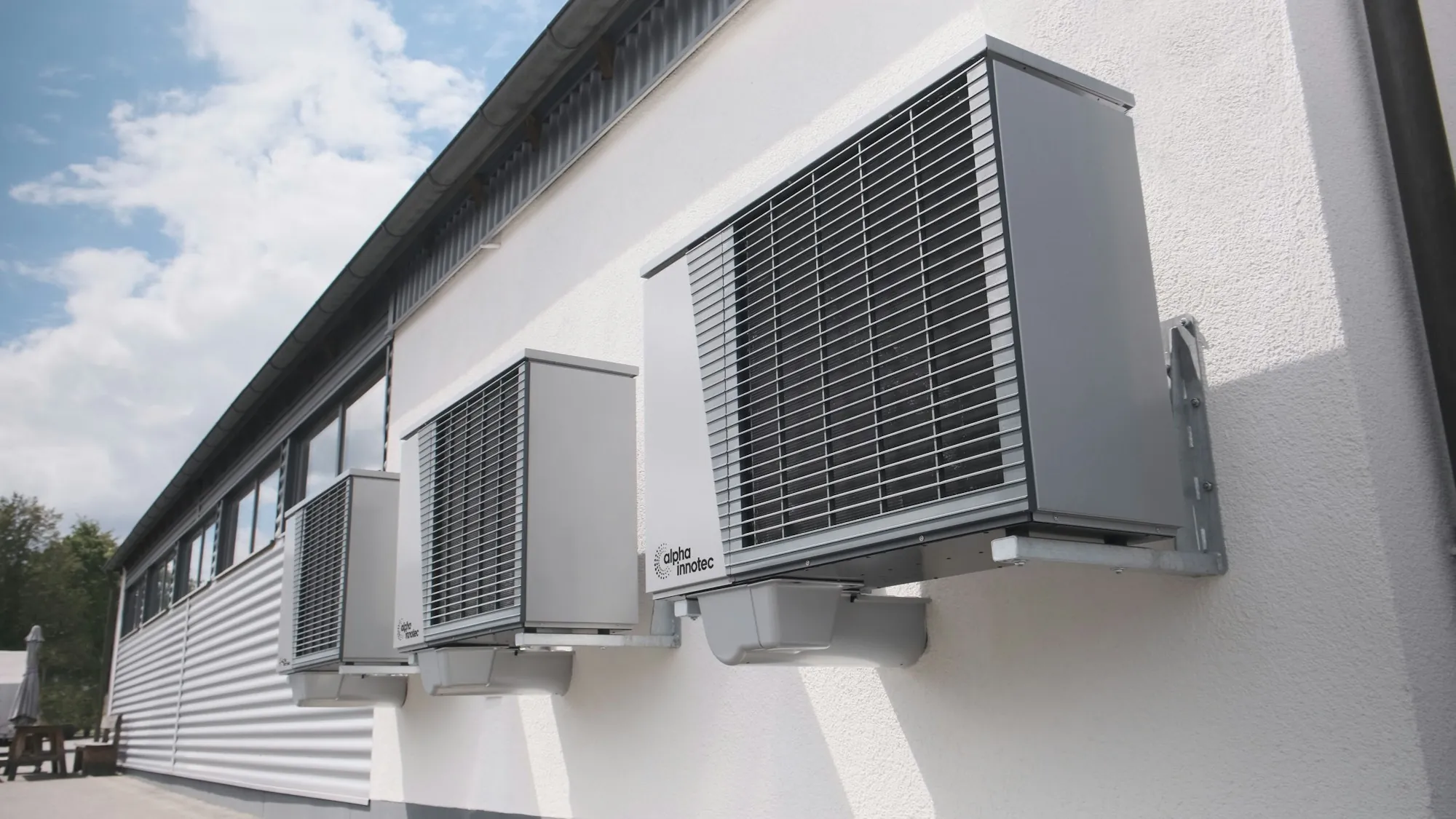 Two heat pump outdoor units on a bright white wall
